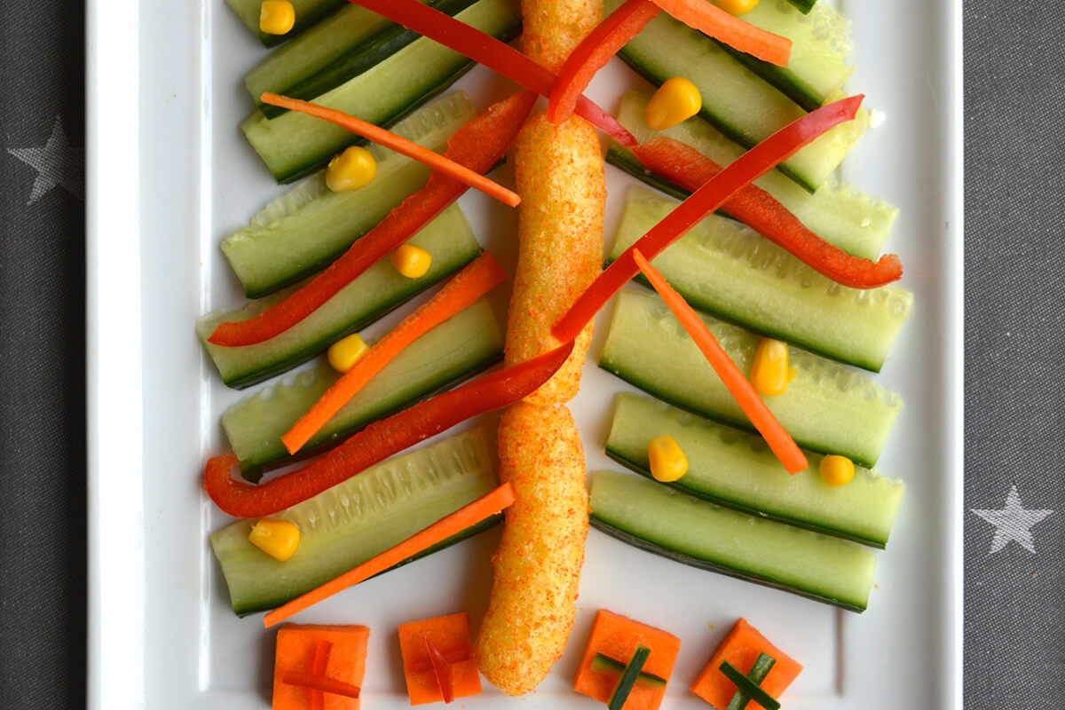 Pepper and carrot placed on top of cucumber tree branches to create tinsel. Sweetcorn placed on top to create baubles